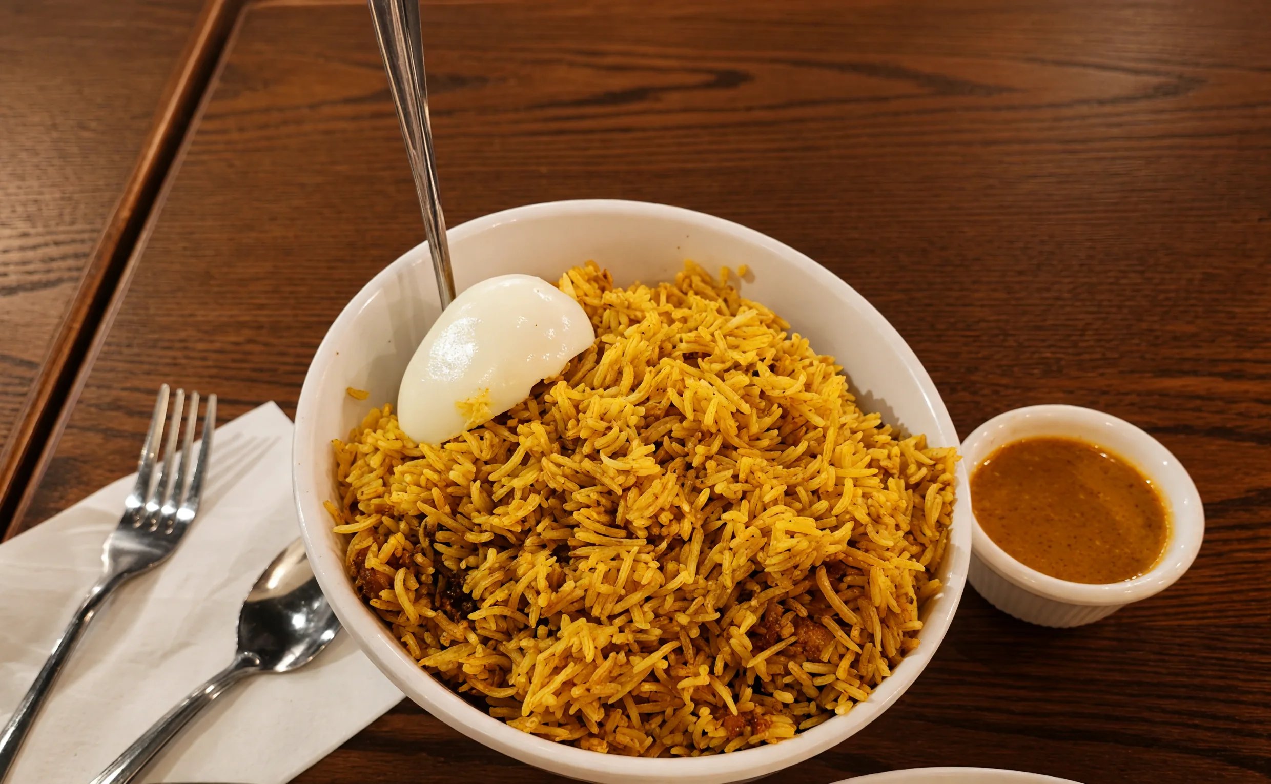 Hyderabadi chicken dum biryani with a boiled egg and a cup of salan at Bawarchi in Mississauga