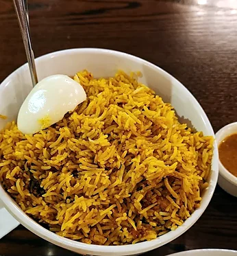 Hyderabadi chicken dum biryani with a boiled egg and a cup of salan at Bawarchi in Mississauga