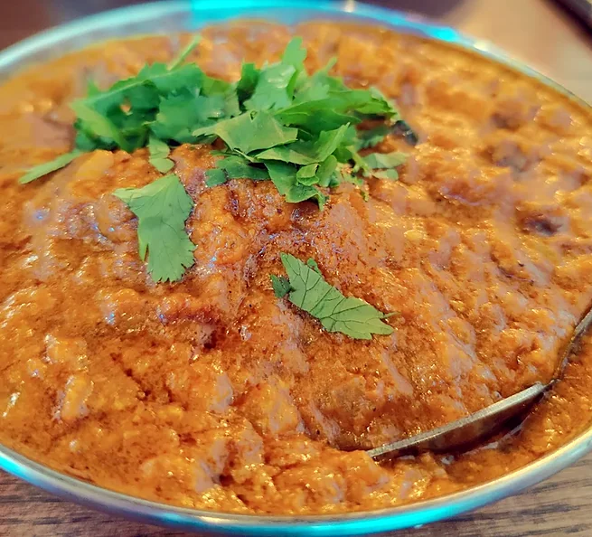 A thick curry topped with fresh coriander in a steel kadai at Bawarchi in Mississauga